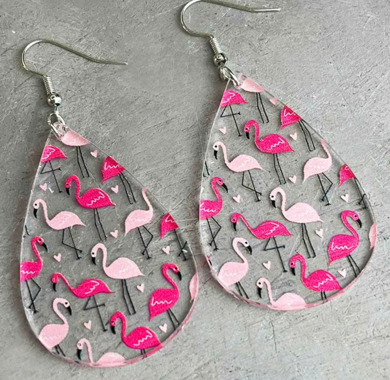 Clear acrylic teardrop earrings with silver hooks featuring a vibrant pattern of light and fuchsia pink flamingos interspersed with tiny white hearts