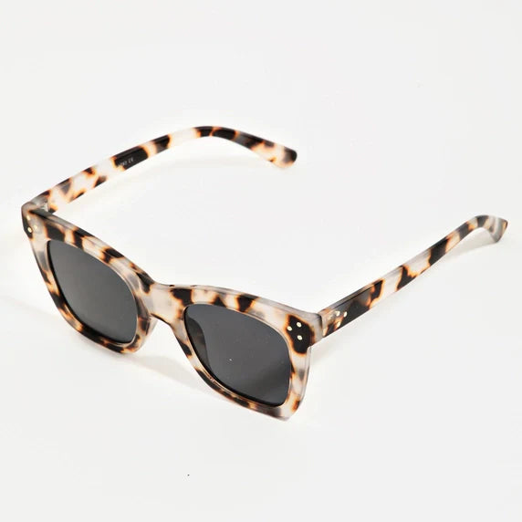 Cat-eye sunglasses featuring a distinctive light brown black and cream tortoiseshell pattern with dark lenses and small gold stud accents displayed on a plain white background