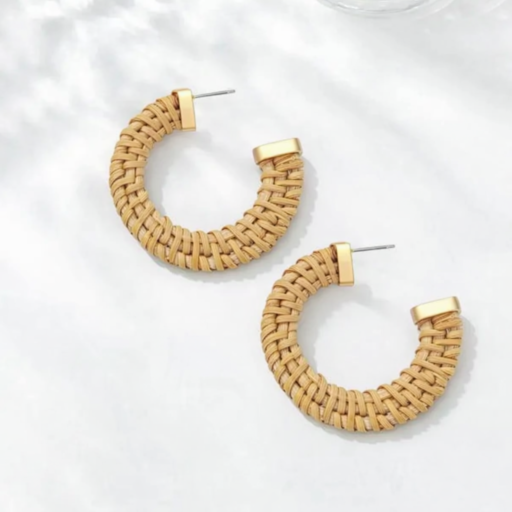 A pair of tan woven rattan C-hoop earrings with matte gold-tone stud posts photographed on a minimalist white surface