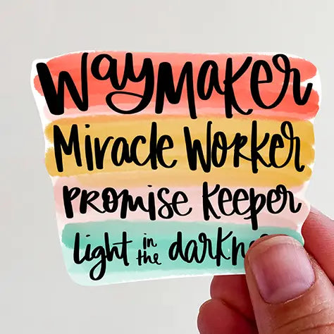 Sticker with black cursive text Waymaker Miracle Worker Promise Keeper light in the dark on a vibrant four-color watercolor striped background in peach, yellow, light pink, and teal, partially held by a person's hand