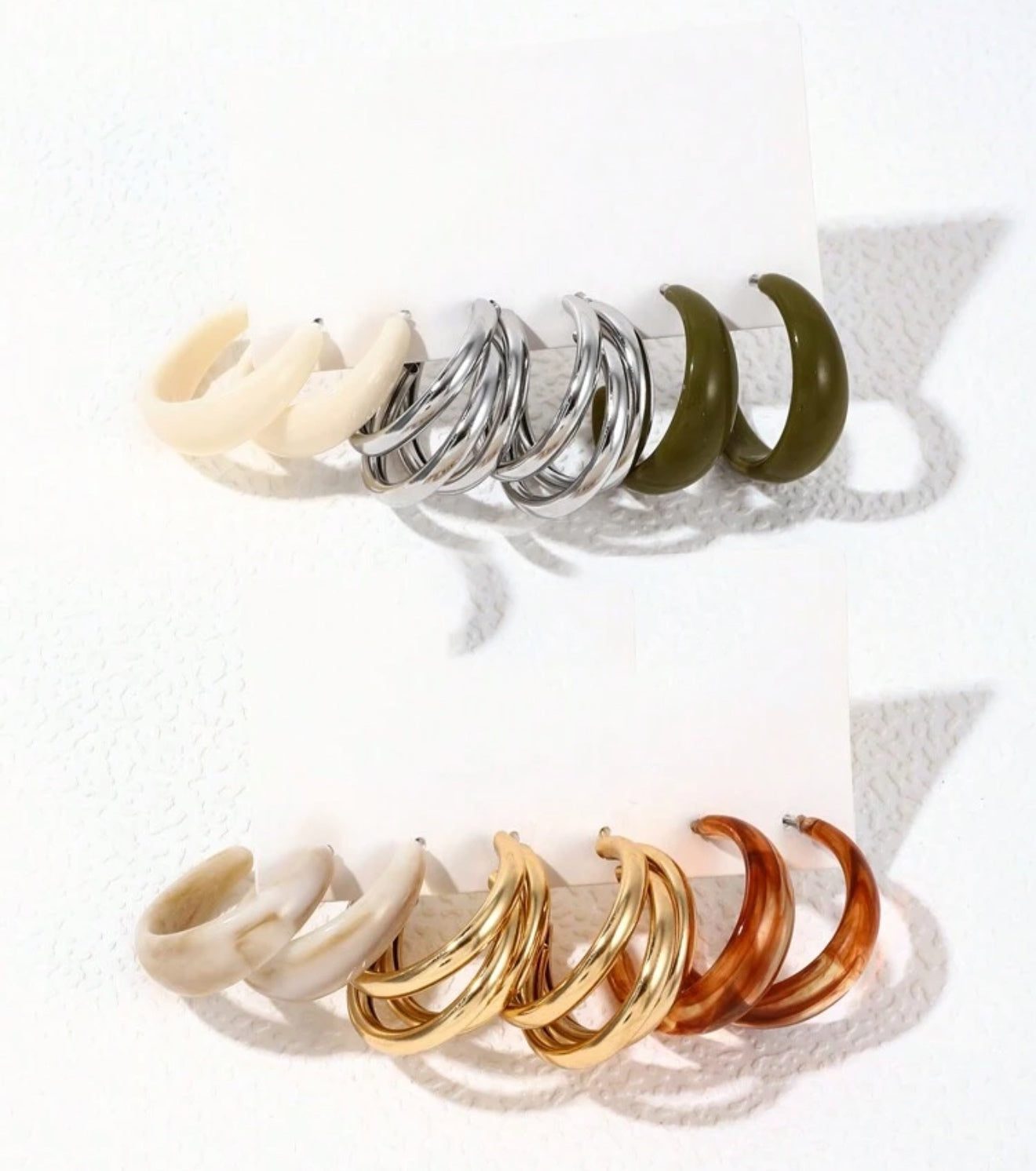 Six pairs of assorted hoop earrings on a white display card featuring cream resin, silver triple layer, olive green resin, marbled beige resin, gold triple layer, and marbled brown resin styles